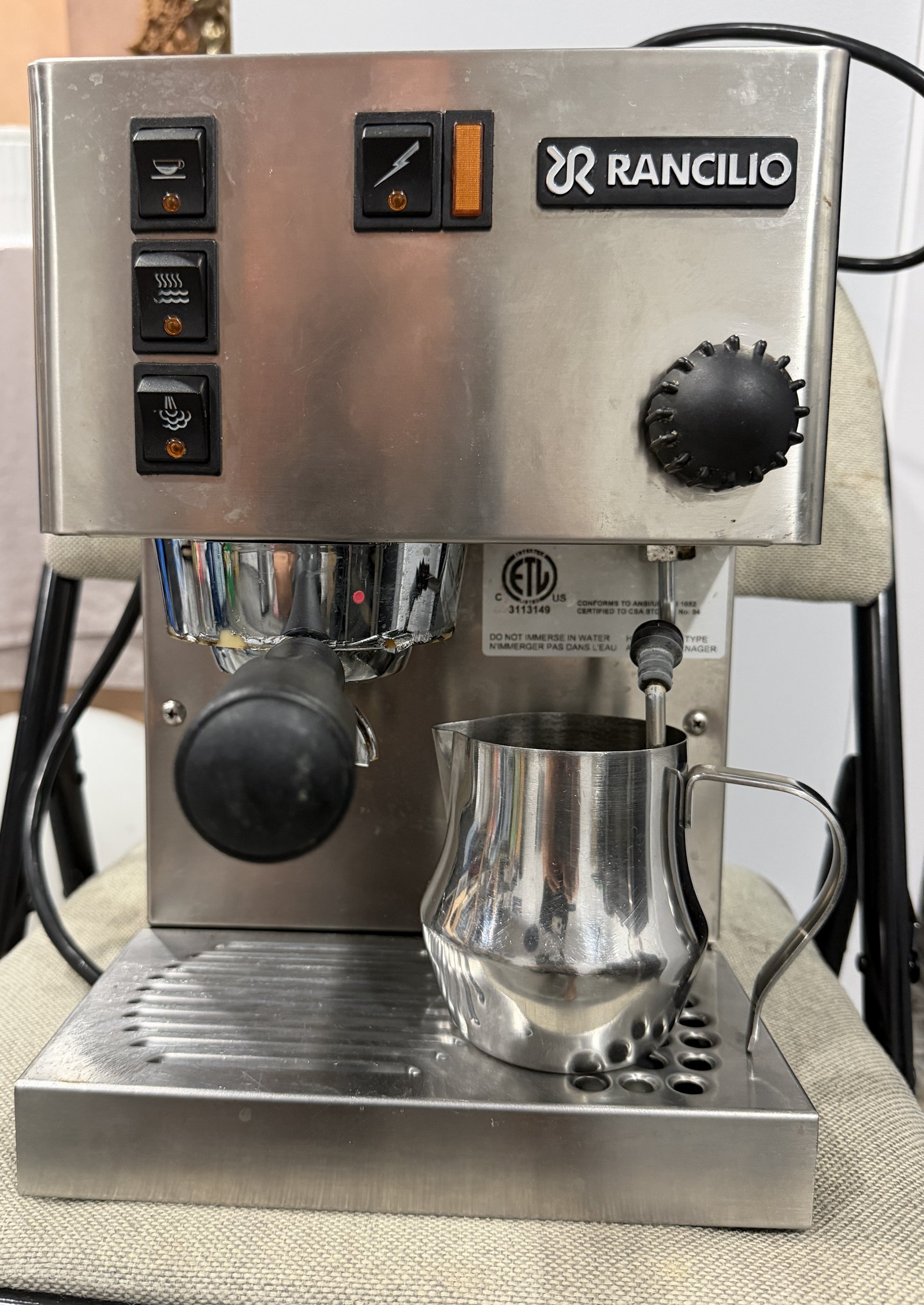 Machine espresso Rancilio en inox de face, porte-filtre en place et pichet a mousser