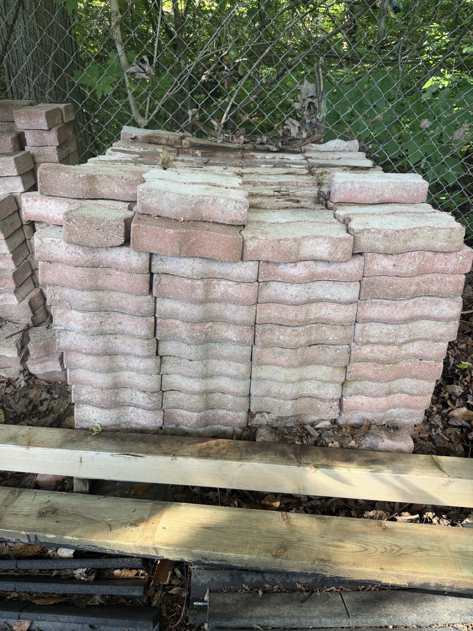 Pavés de béton à profil ondulé empilés en rangs, teinte rosée