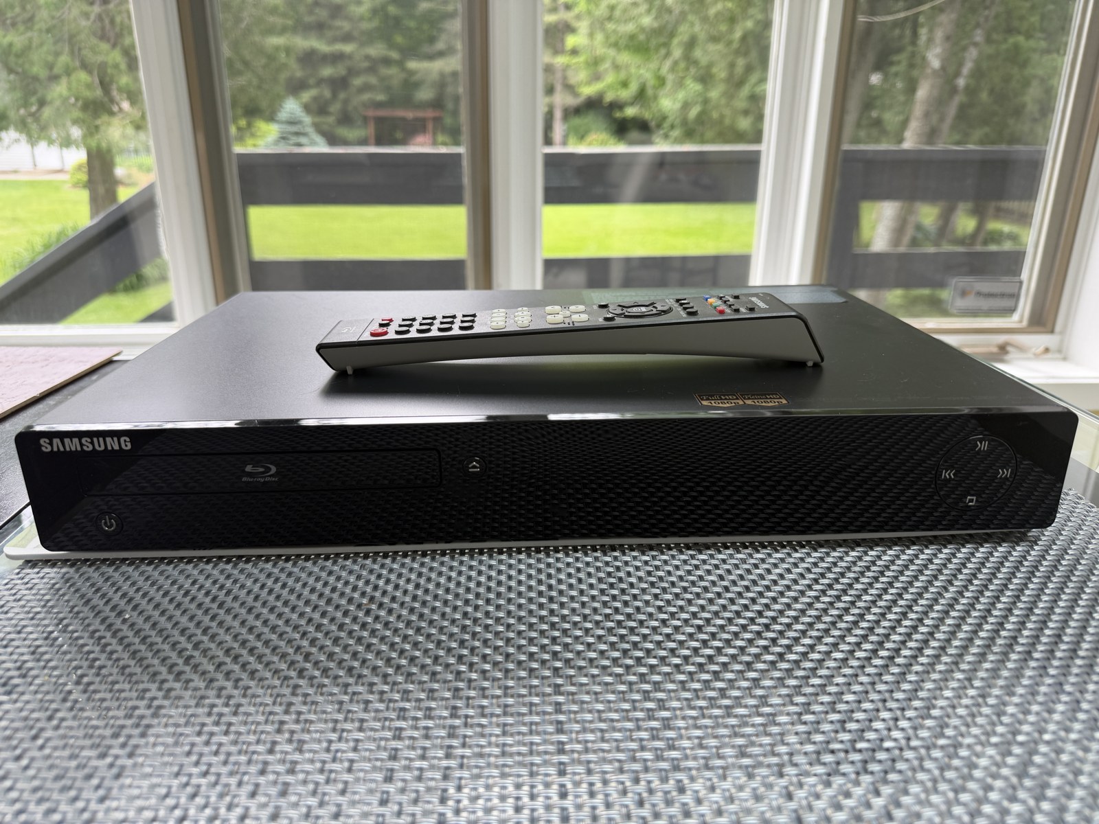 Lecteur Blu-ray Samsung BD-P1500 de face, avec sa télécommande posée dessus