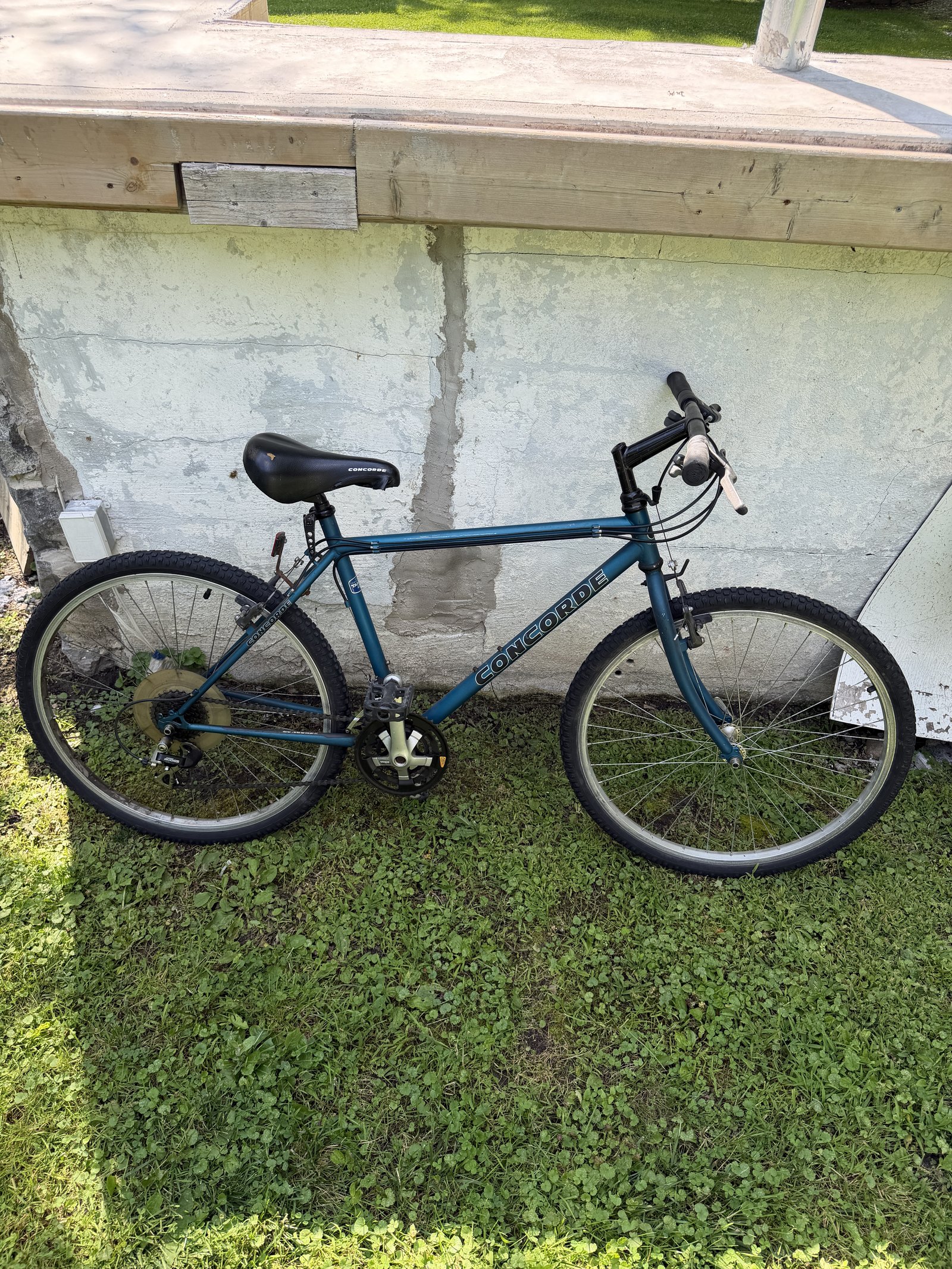 Vélo Concorde bleu sarcelle appuyé contre un mur, vue de profil complète