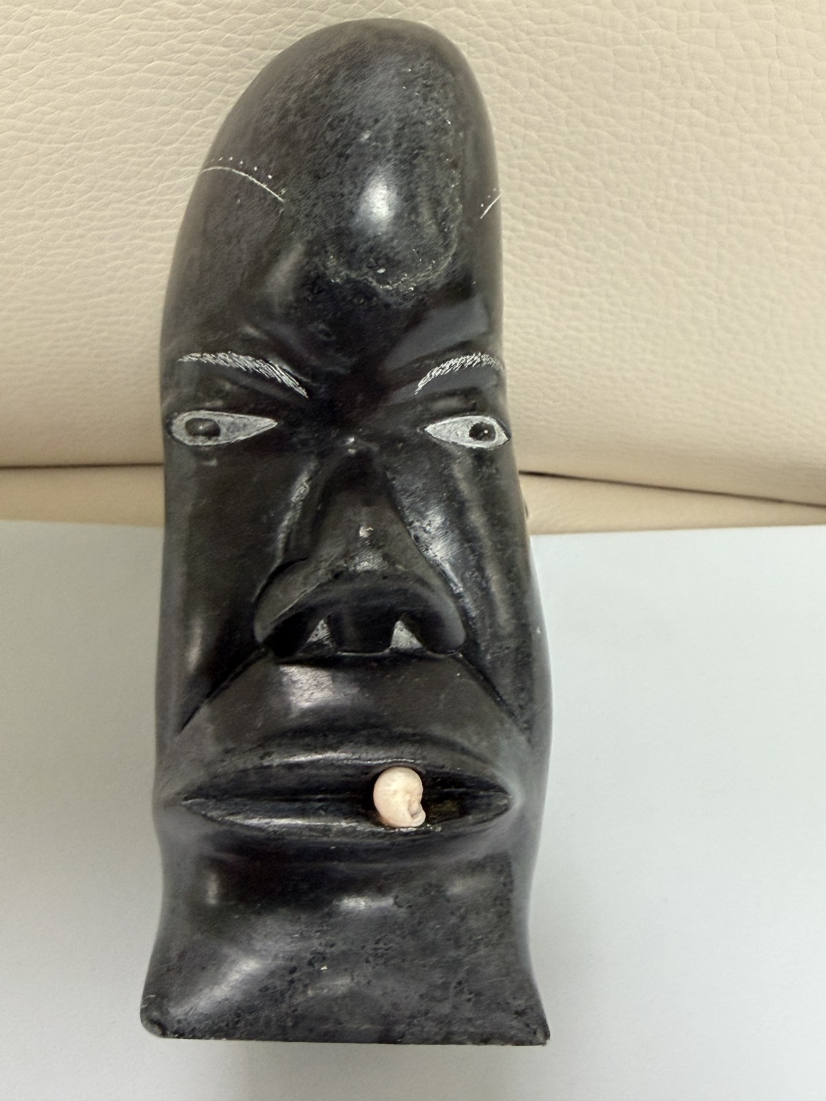 Visage inuit sculpté en pierre sombre, dent en os incrustée